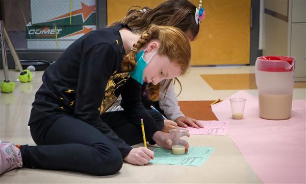 Girls write down science observations